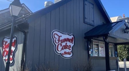 Dark grey Funnel cake building with sign and ordering window