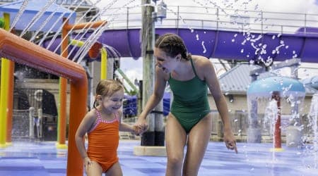 girl getting splashed at shoreline sprayground water attraction