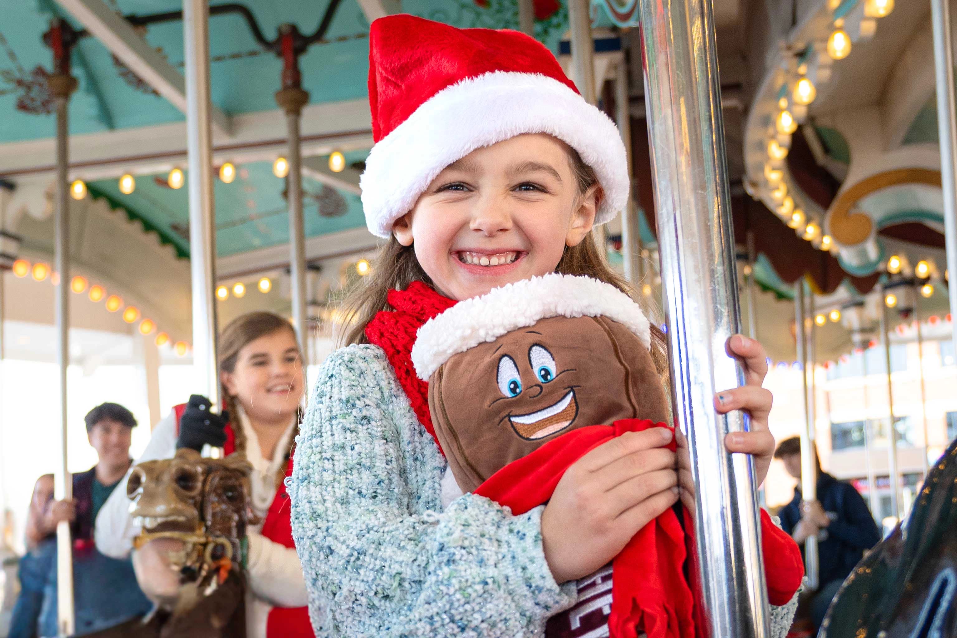 23.HP.CCL.Carrousel.On Ride.Young Girl Smiling AT Camera.Santa Hat.Hershey Bar Plush